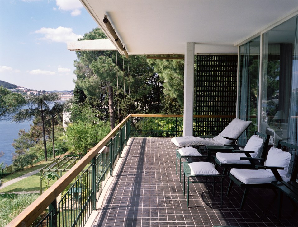 Modern terrace with lounge chairs overlooking the Sea of Marmara, with pine trees and white sun umbrella.