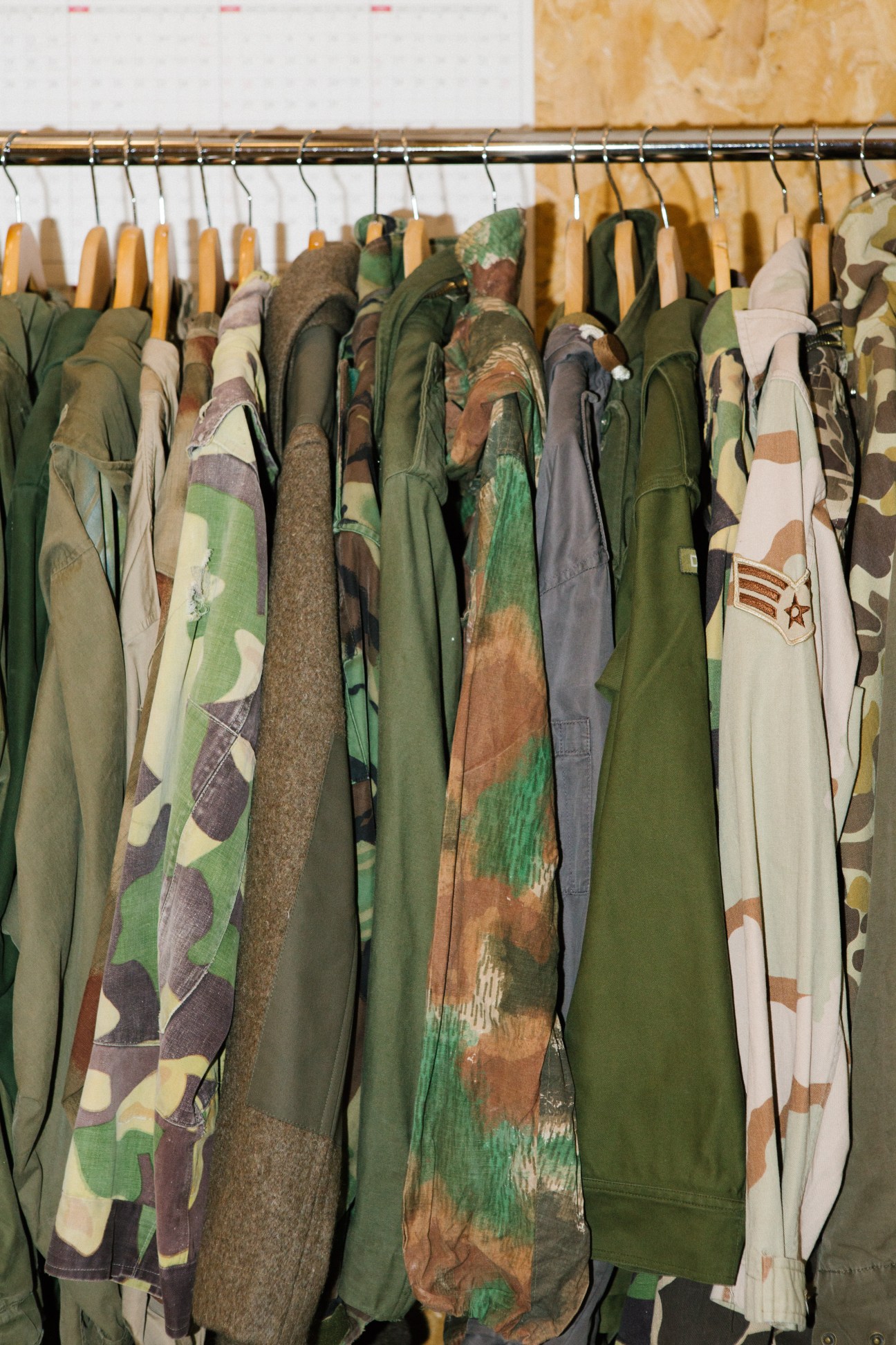 Collection of vintage workwear garments in various colors and patterns hanging on a metal rod
