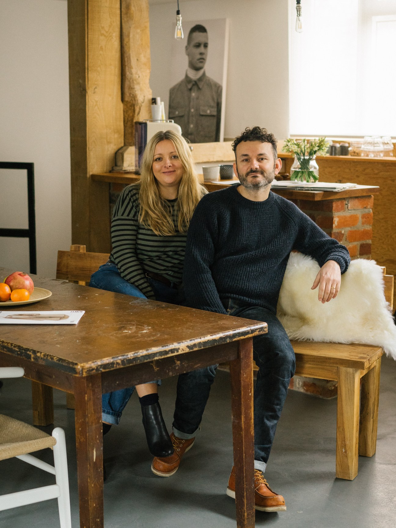 Charlotte and Adam Cameron sitting together at a wooden table in their studio space