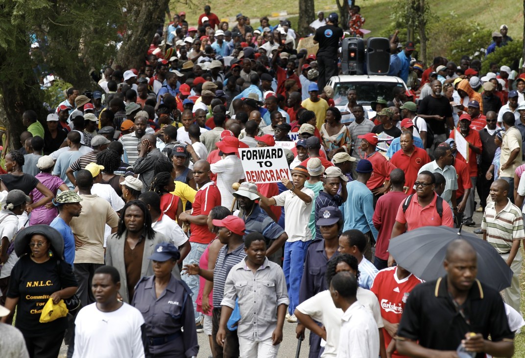 Large crowd of African protesters gathered outdoors holding a sign that reads 'Forward to Democracy'