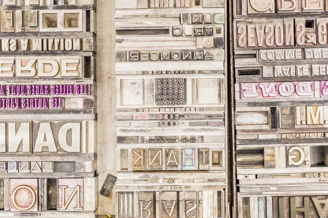 Organized metal typographic letter blocks and printing characters arranged in wooden compartments.