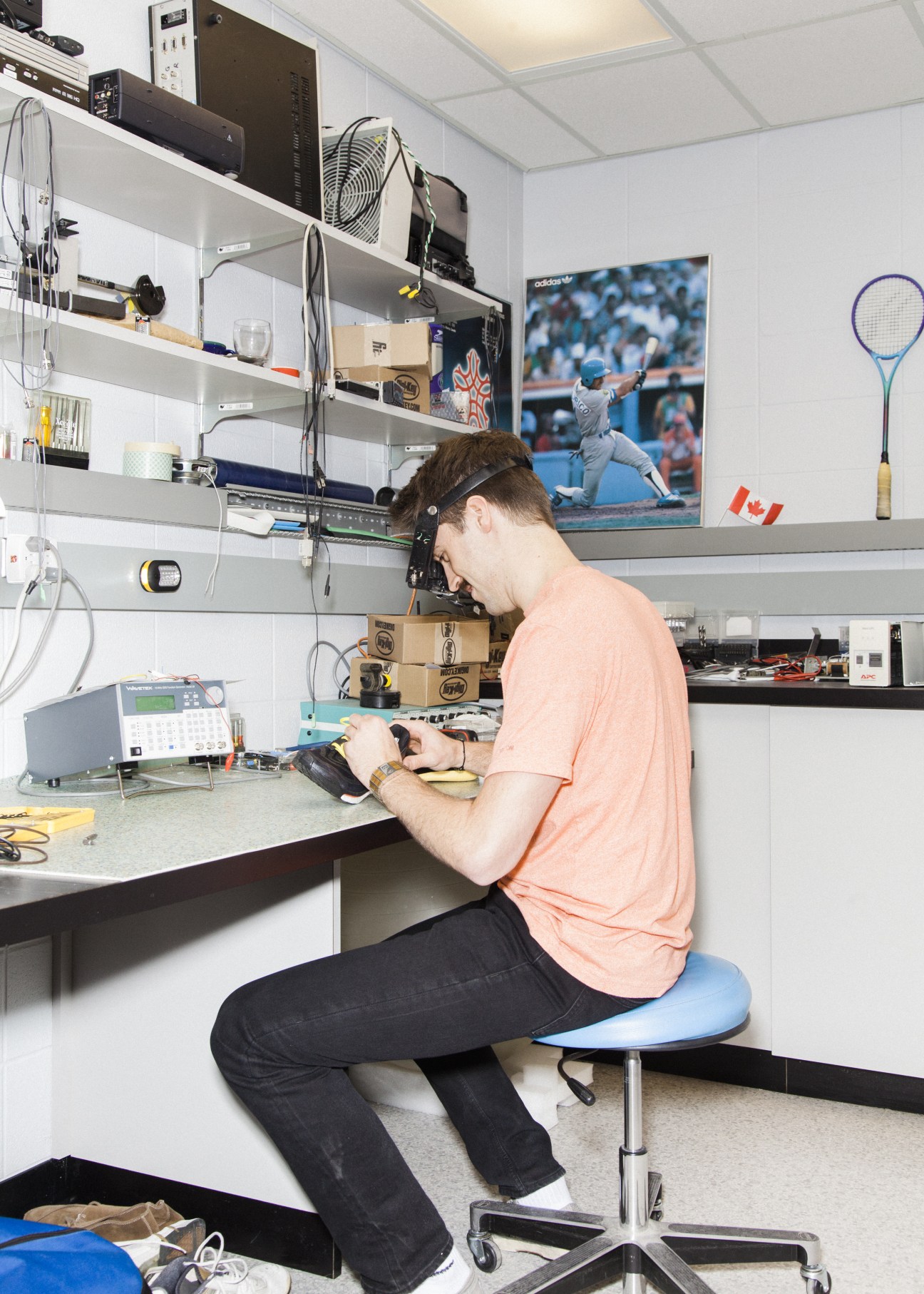 Research assistant Ryan Madden works at a lab bench surrounded by shelves of equipment and testing devices.