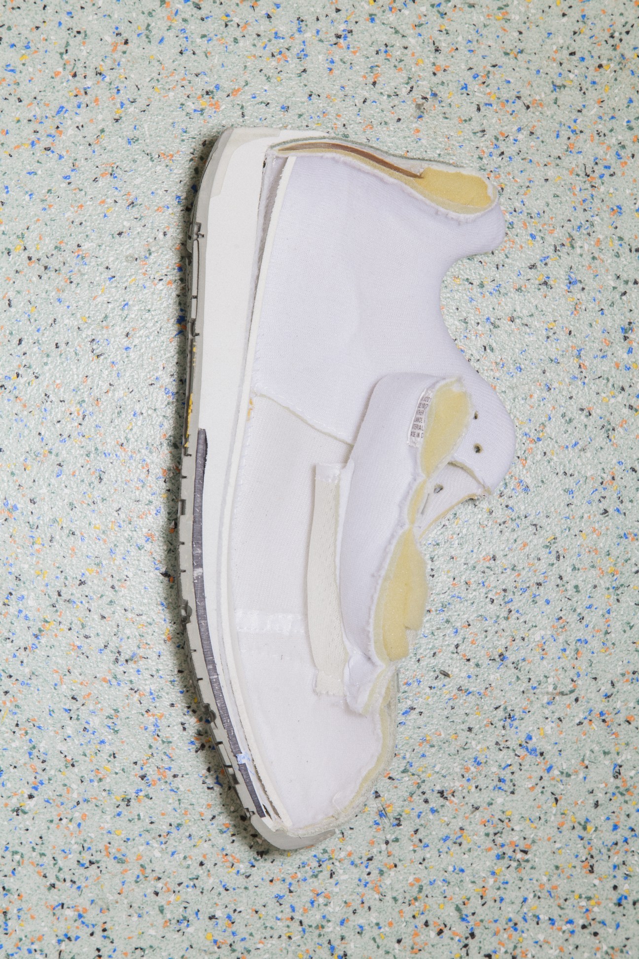 White running shoe cut lengthwise to reveal internal cushioning and sole composition.