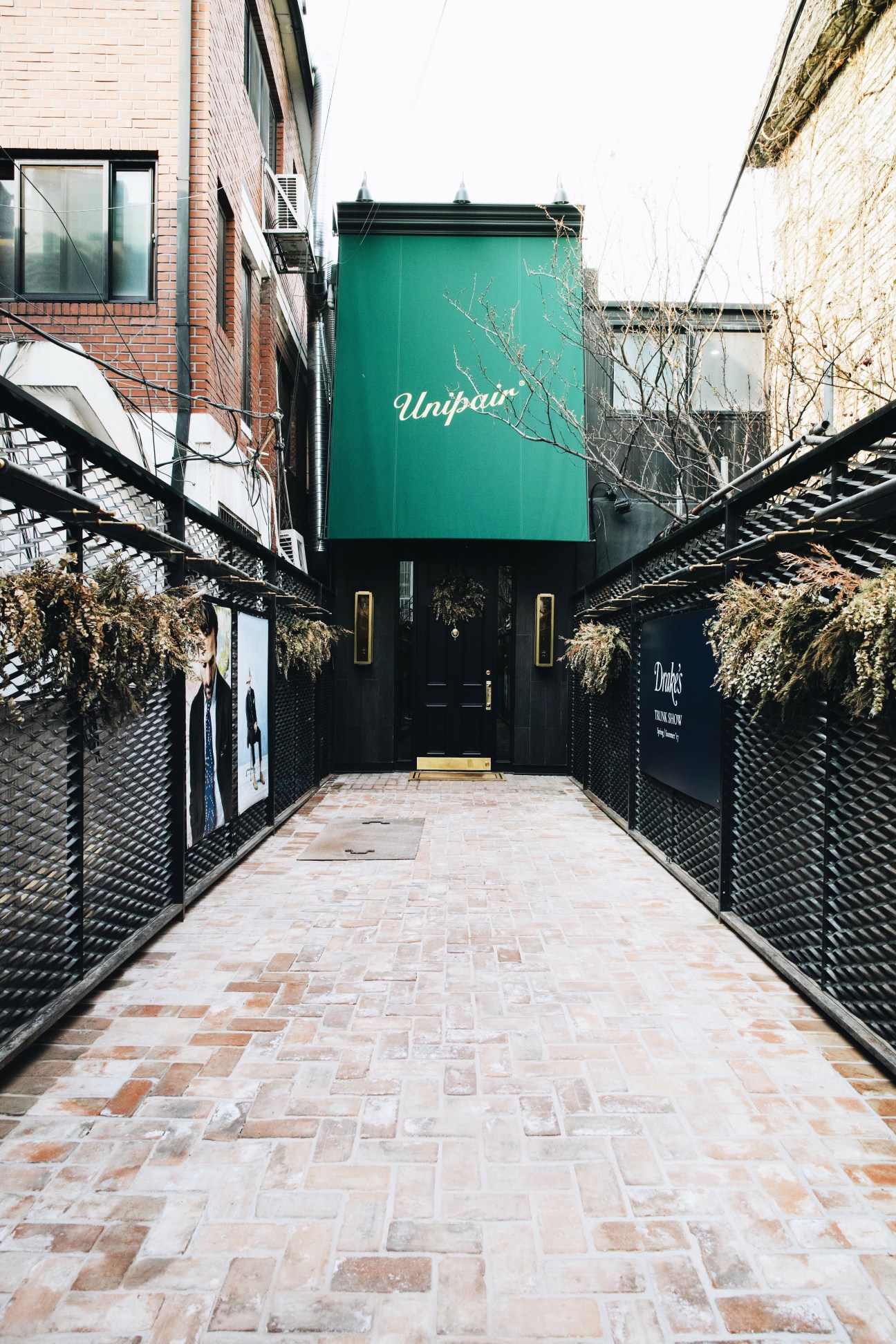 Unipair shoe shop exterior with green signage and black entrance gate in Seoul alley