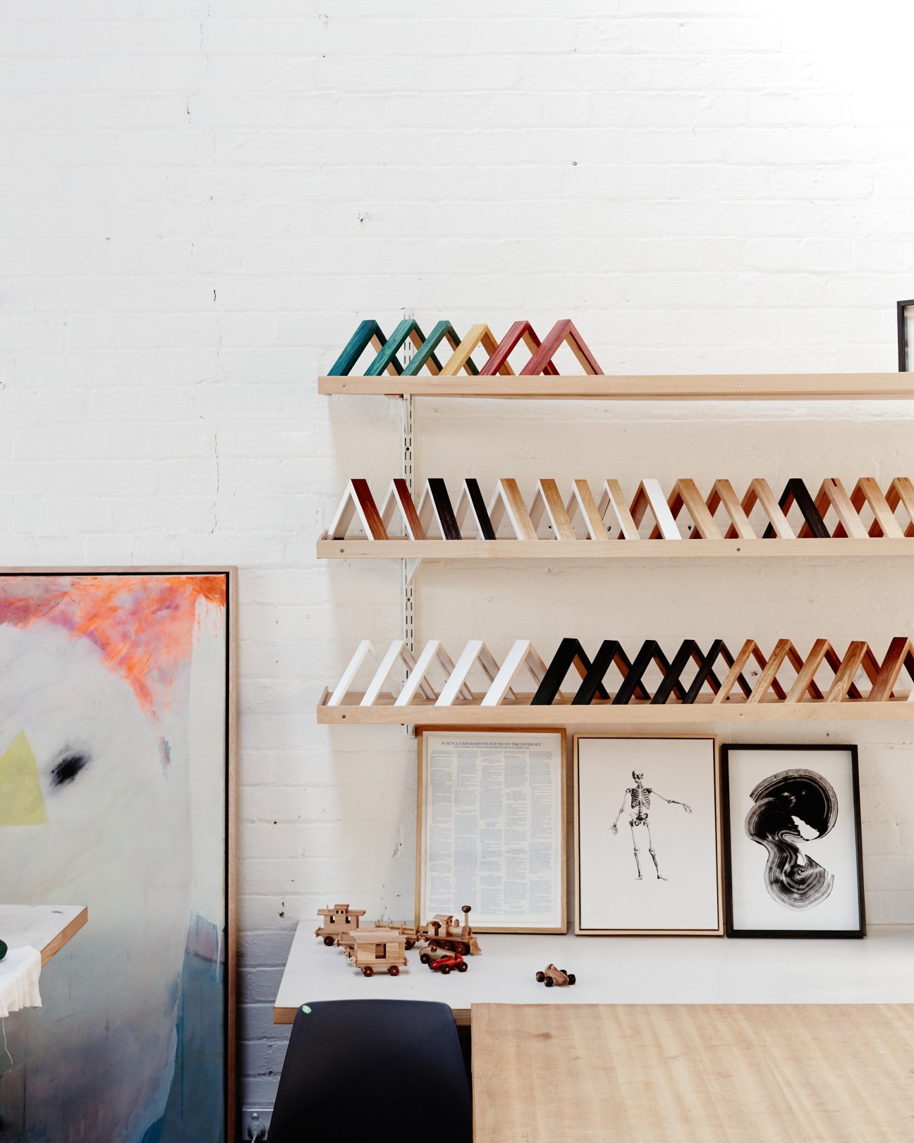 Wooden shelves displaying colorful fabric samples and framed artwork in a bright studio space.