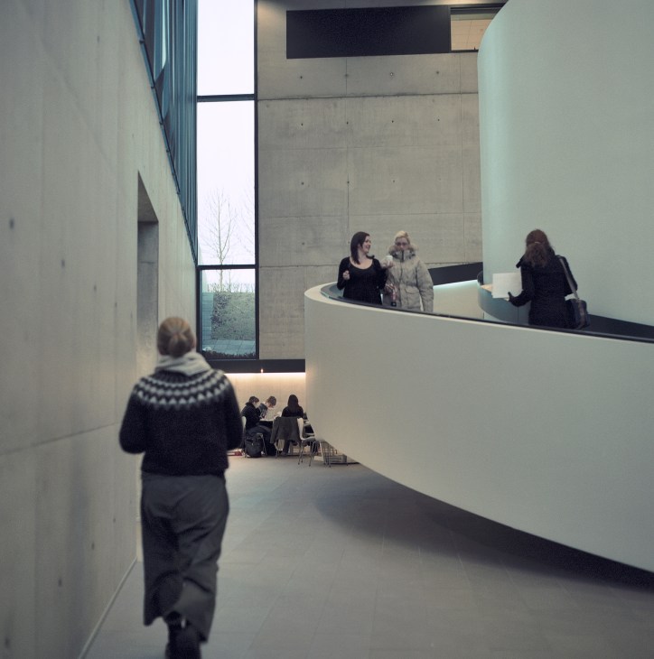 Interior hallway of University of Iceland's Oddi building with concrete walls and people walking.