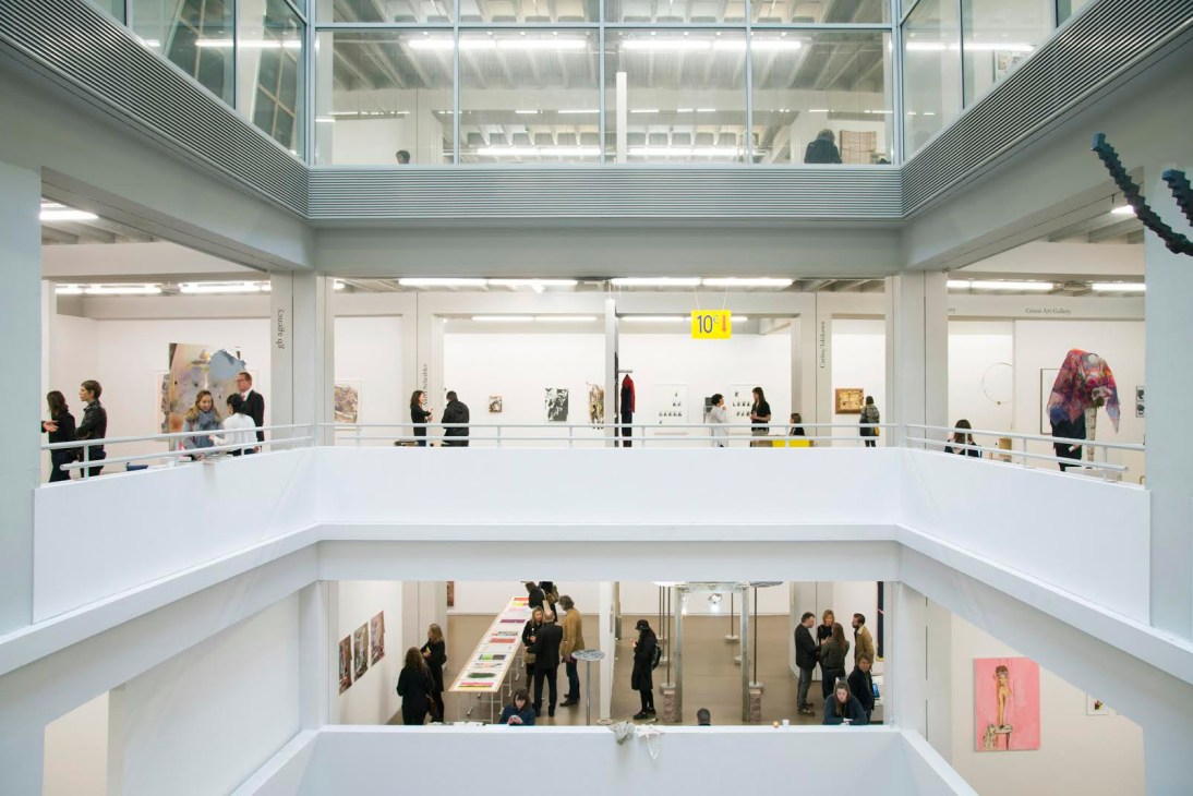 Interior view of Independent Brussels 2016 art fair with multiple levels of white gallery spaces and visitors browsing artworks.