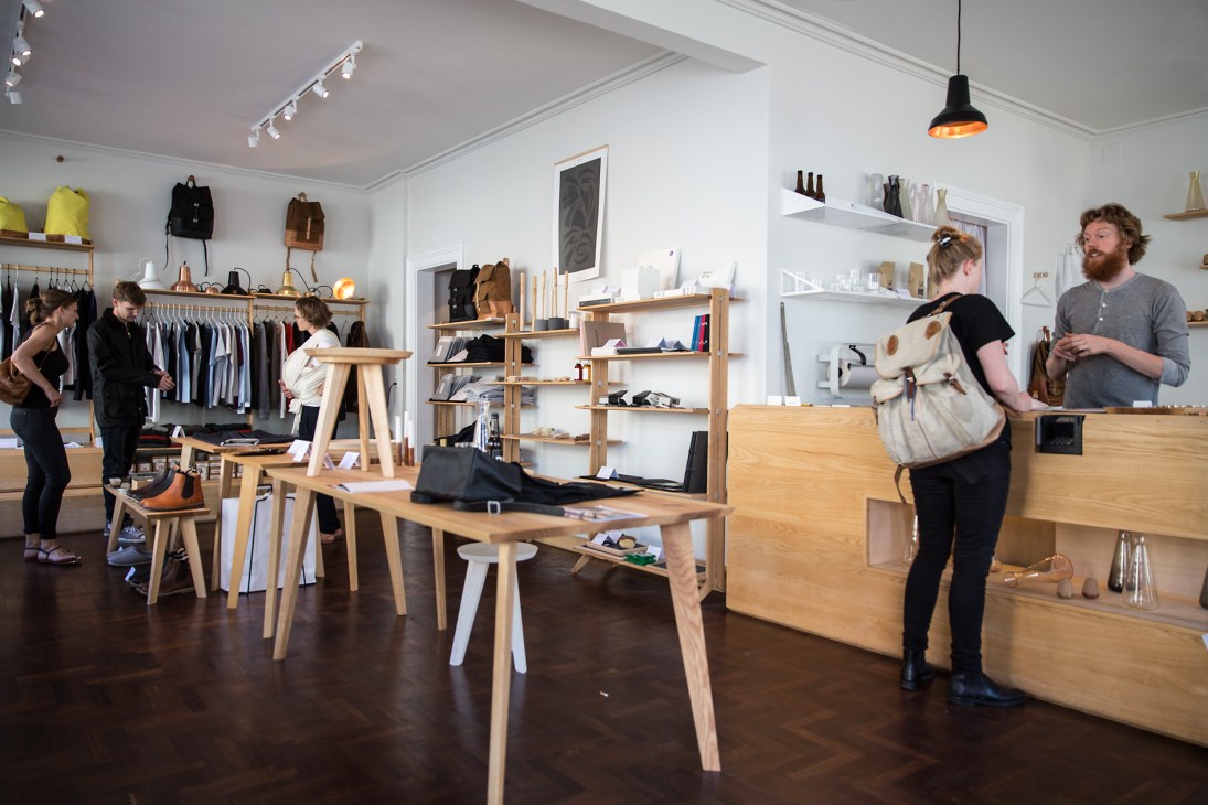 Interior of Soeder shop showing wooden furniture, shelving, clothing racks, and customers browsing sustainably produced homeware and essentials.