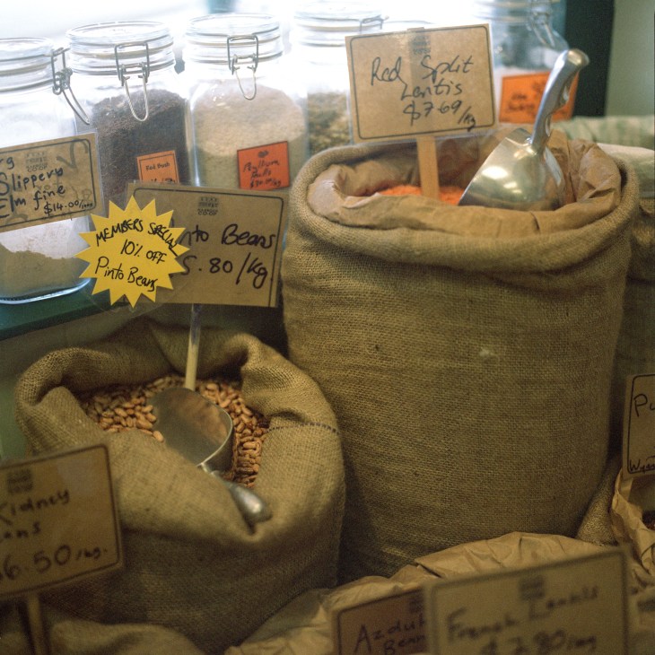 Bulk bins of dried beans and lentils with handwritten price labels at Harbour Co-op.