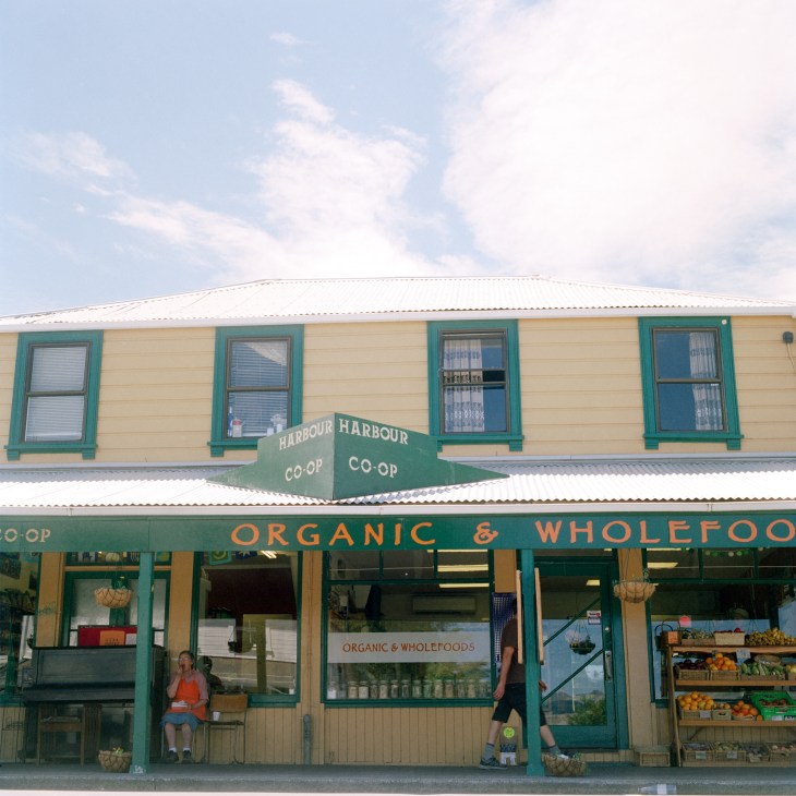 Harbour Co-op storefront in Lyttelton, New Zealand, with green and cream exterior, displaying organic and wholefoods signage.