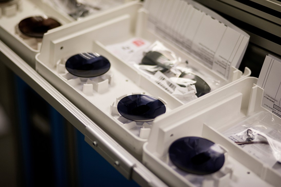 Dark blue lens discs arranged in a white storage tray ready for eyeglass frame assembly.