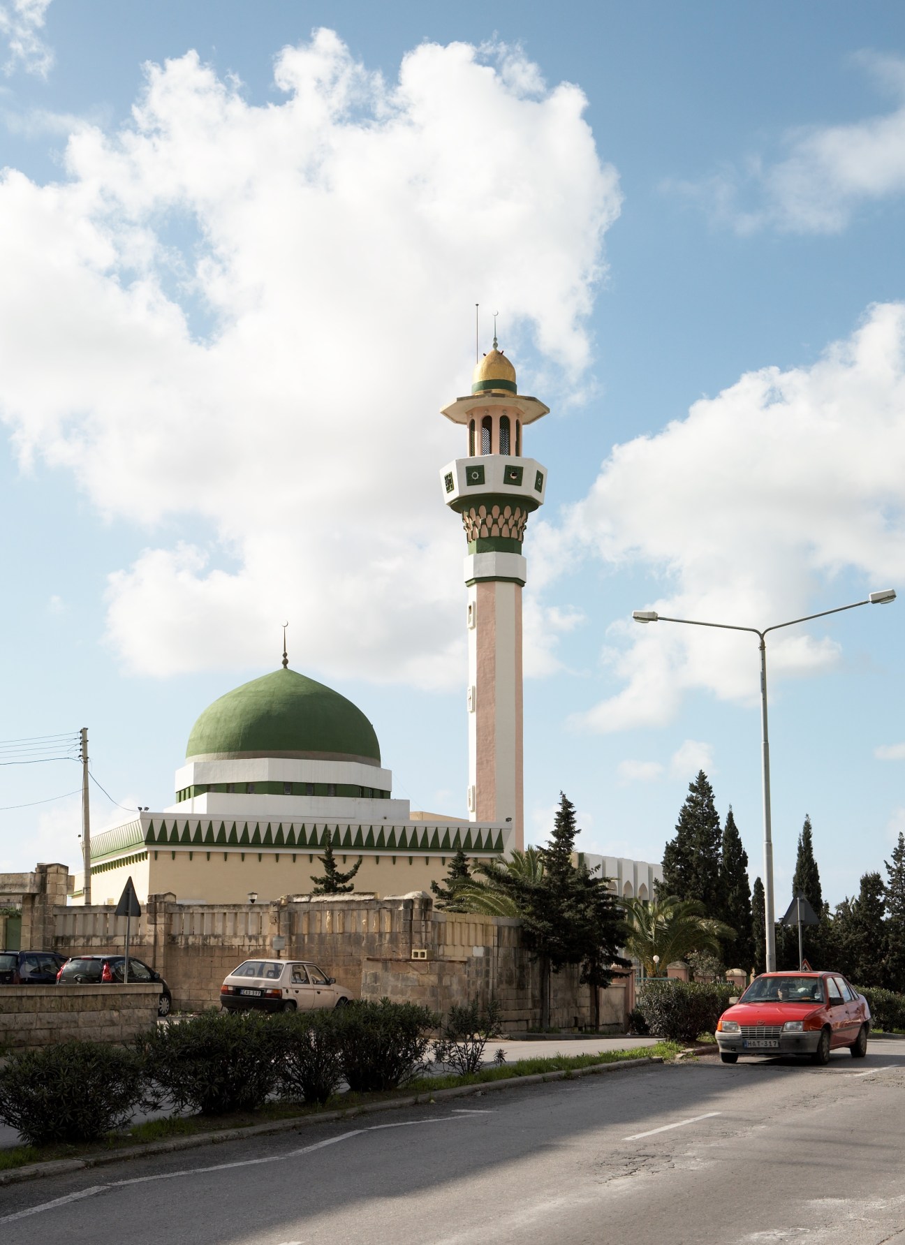 The Islamic Centre mosque with green dome and tall minaret under blue sky with clouds