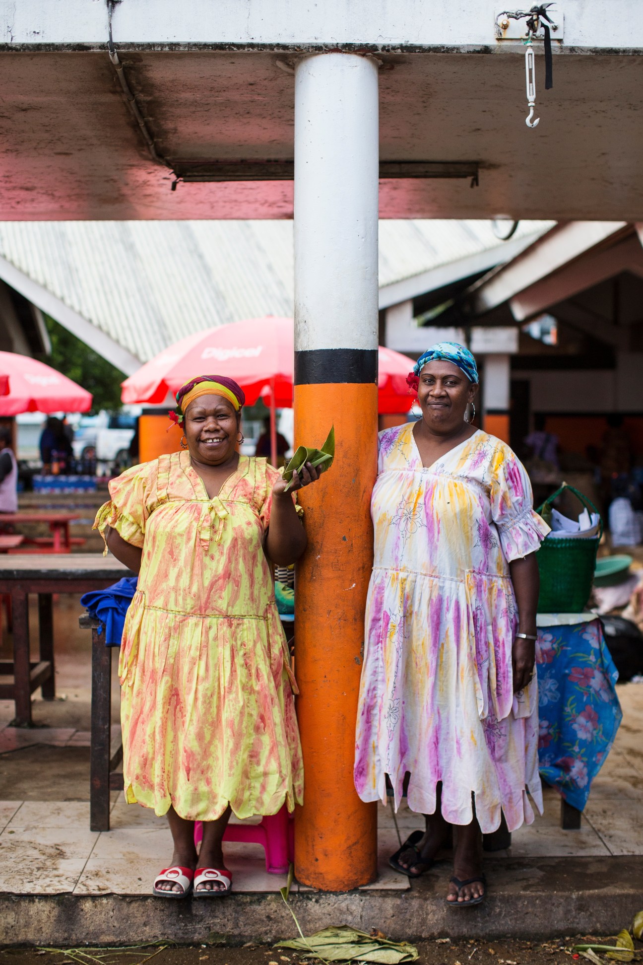 Two women fruit and vegetable vendors smile at Port Vila market in Vanuatu.
