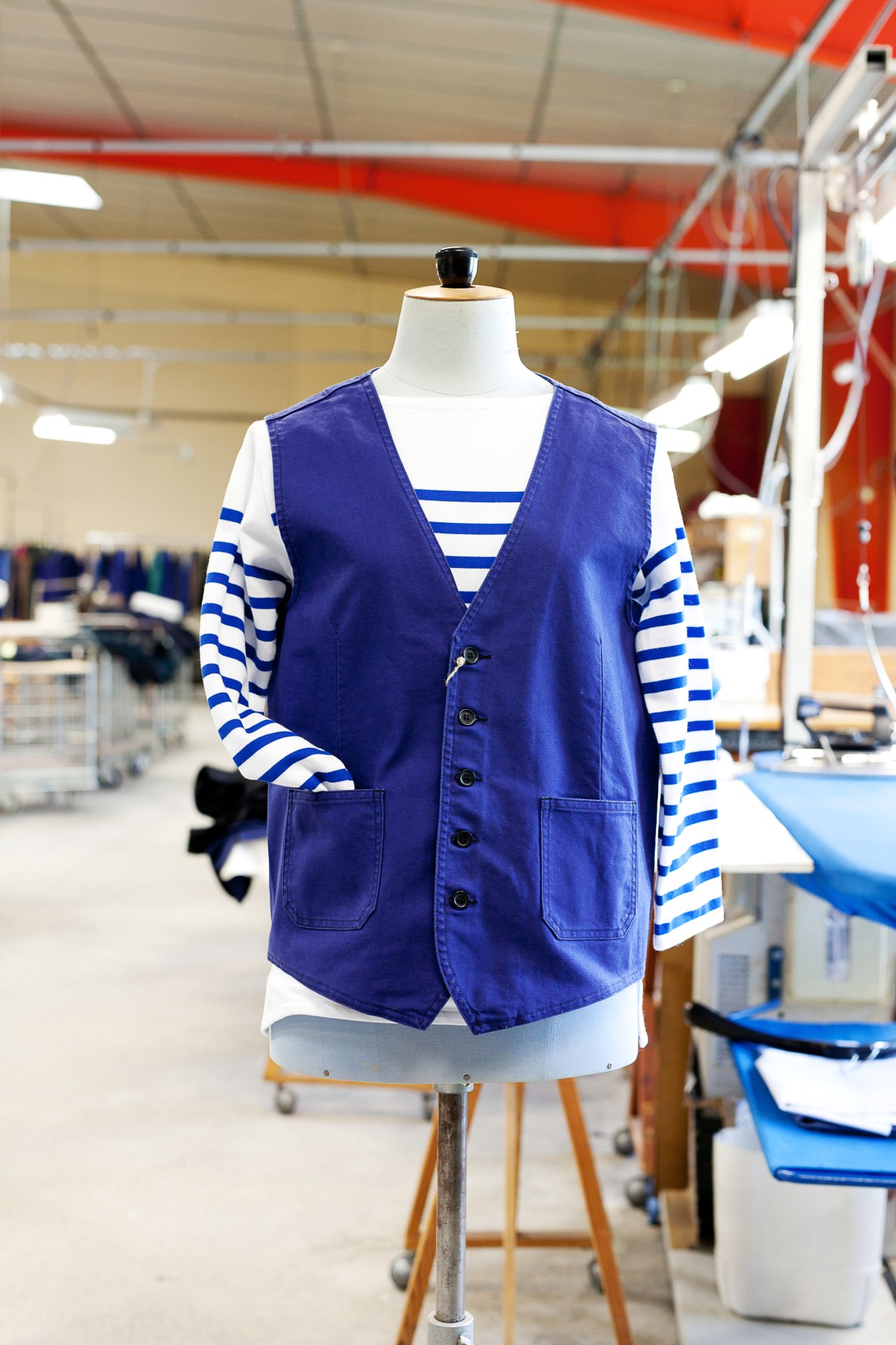 Navy sleeveless vest over blue and white striped mariner shirt on dress form in factory.