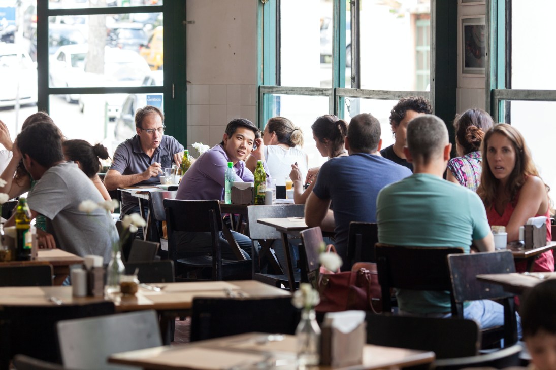 Sabiá bar at lunchtime with diners seated at tables by large windows.