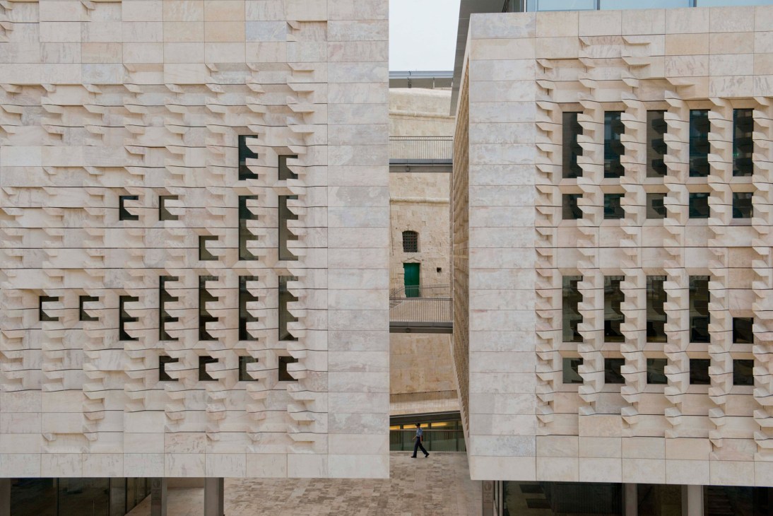 Malta's Parliament House exterior designed by Renzo Piano, featuring textured stone facade with geometric window patterns.