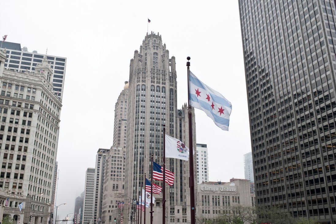 Chicago downtown skyline with historic and modern buildings, flags, and Chicago Tribune building visible.