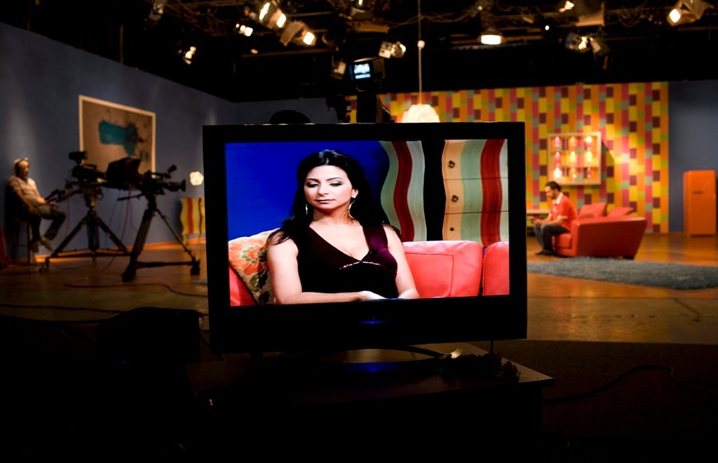Zeina Daccache displayed on a monitor screen inside a television studio set.