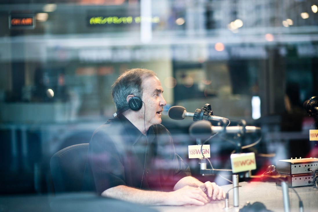 Rick Kogan speaking into a microphone while wearing headphones in a radio studio.