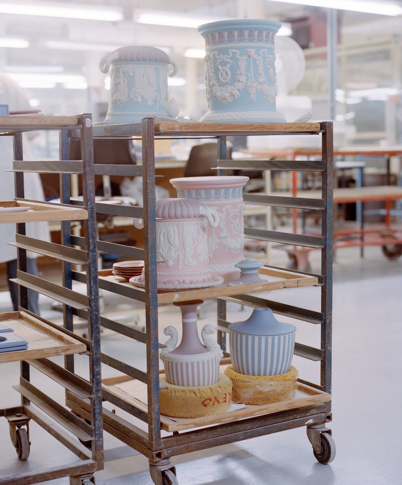 Borghese vases in various stages of production displayed on a wooden factory cart with metal frame in a Wedgwood factory.