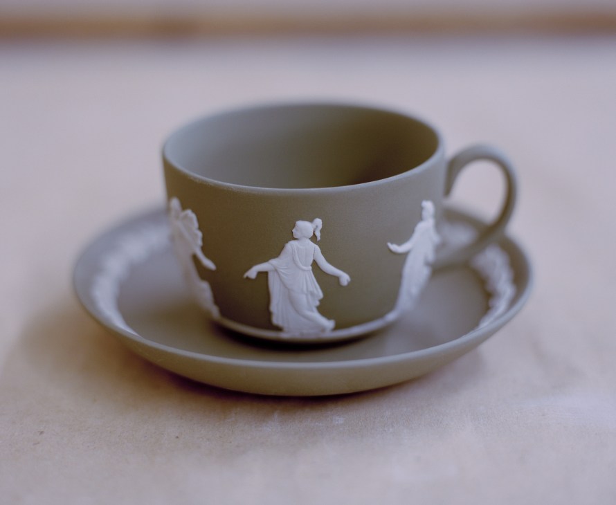 A pale green and white Wedgwood Jasperware teacup and saucer with classical relief figures.