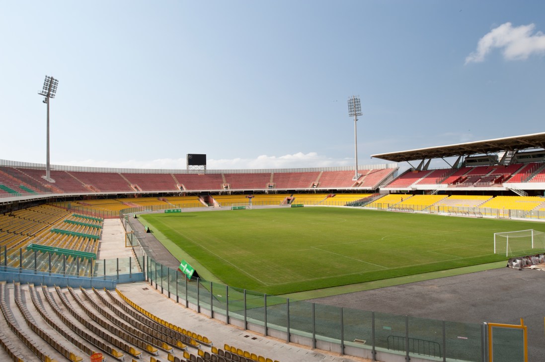 Accra Sports Stadium with colorful seating, floodlights, and a pristine grass pitch.