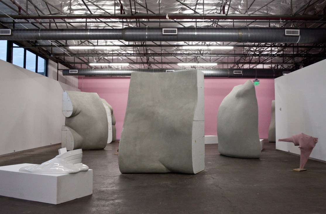 Erwin Wurm's abstract sculptural installation with large cream-colored forms in an industrial gallery space with pink walls.