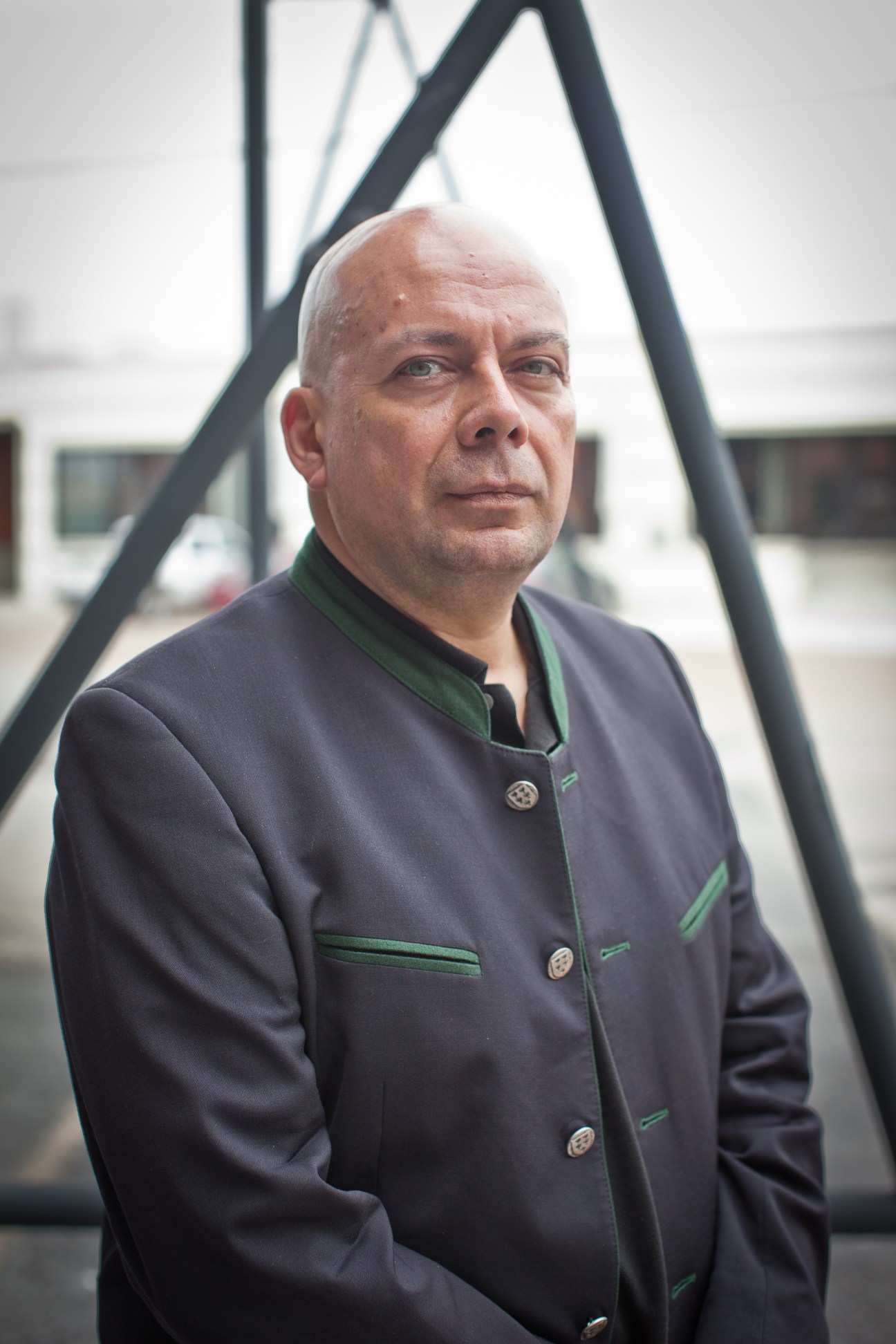 Peter Doroshenko, director of Dallas Contemporary, stands in front of a large black triangular sculpture.