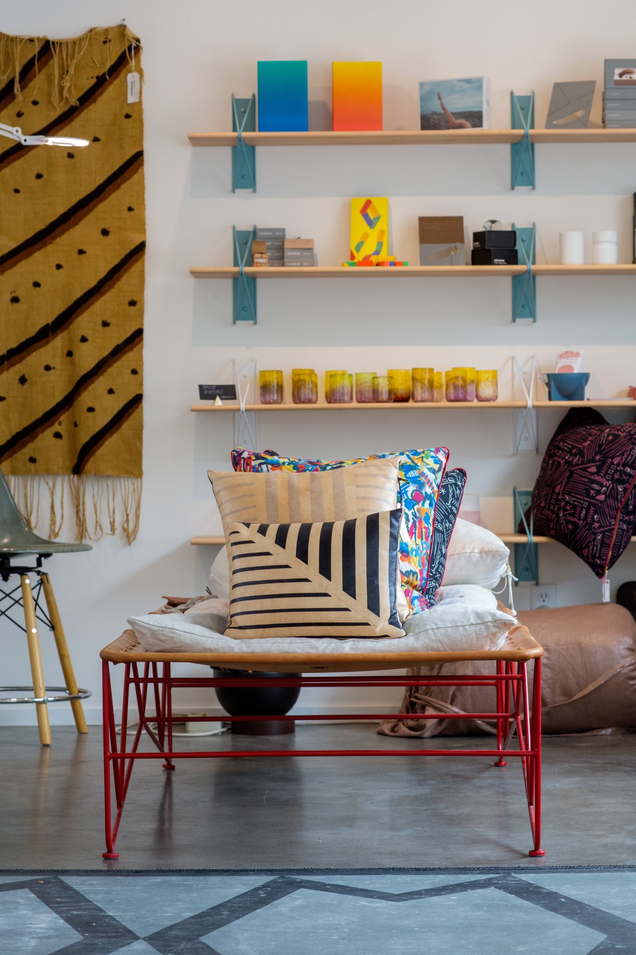 Interior of Wilder design shop displaying colorful cushions, art books, and decorative objects on wooden shelves.