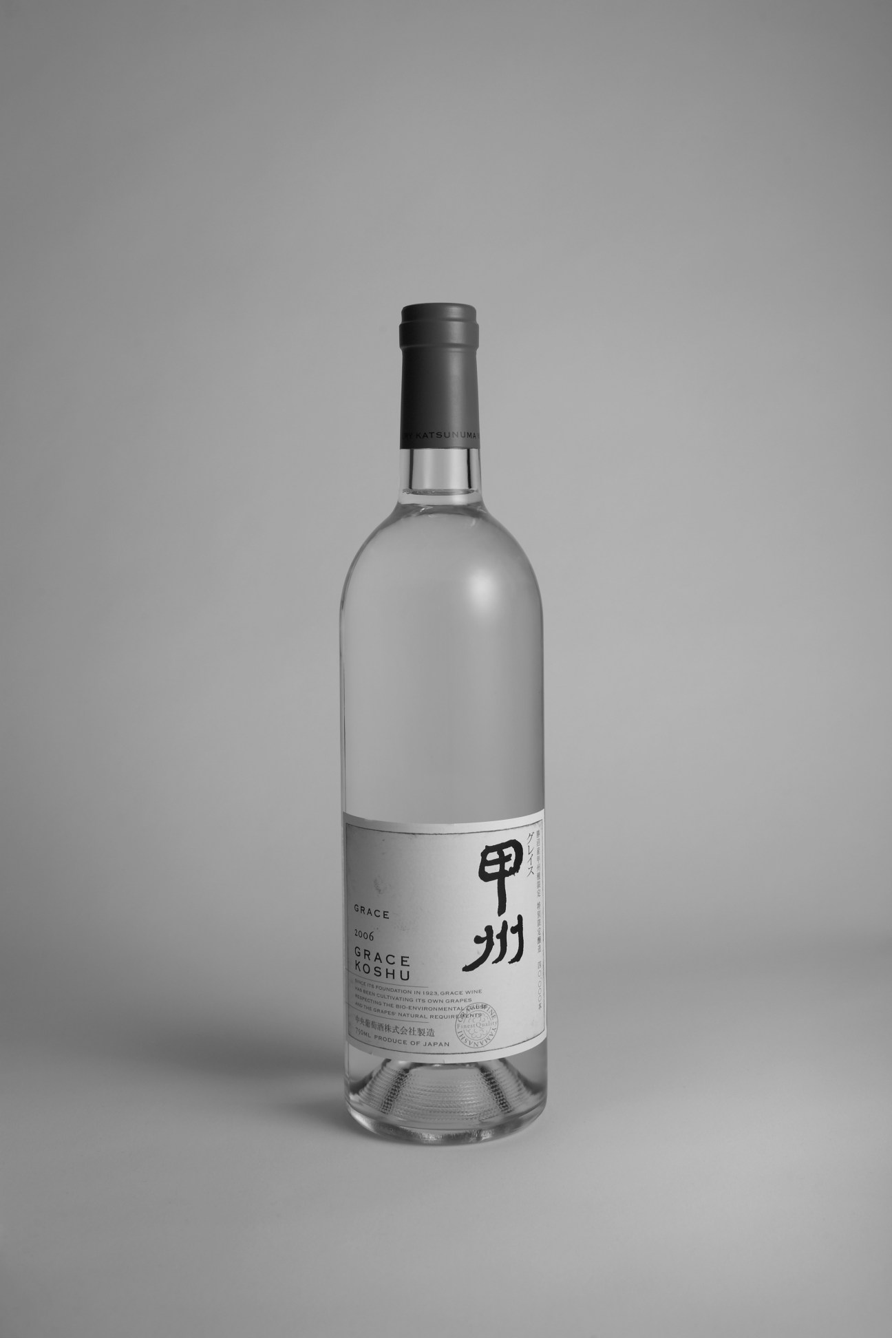 Grace Koshu white wine bottle from Yamanashi, Japan, with black cap and white label against gray background.