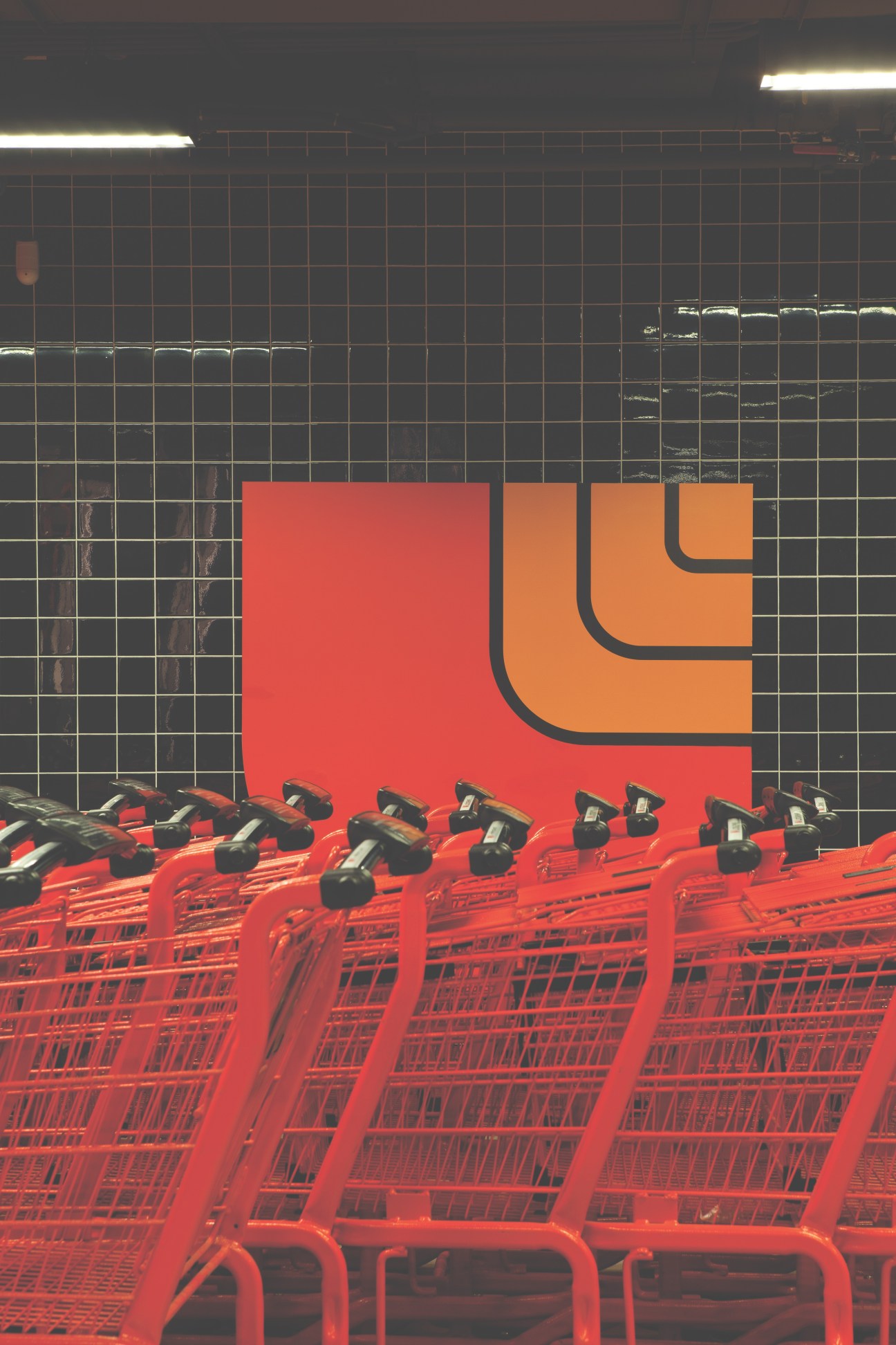 Red Loblaws shopping carts lined up against a black tiled wall with orange and red branding signage.