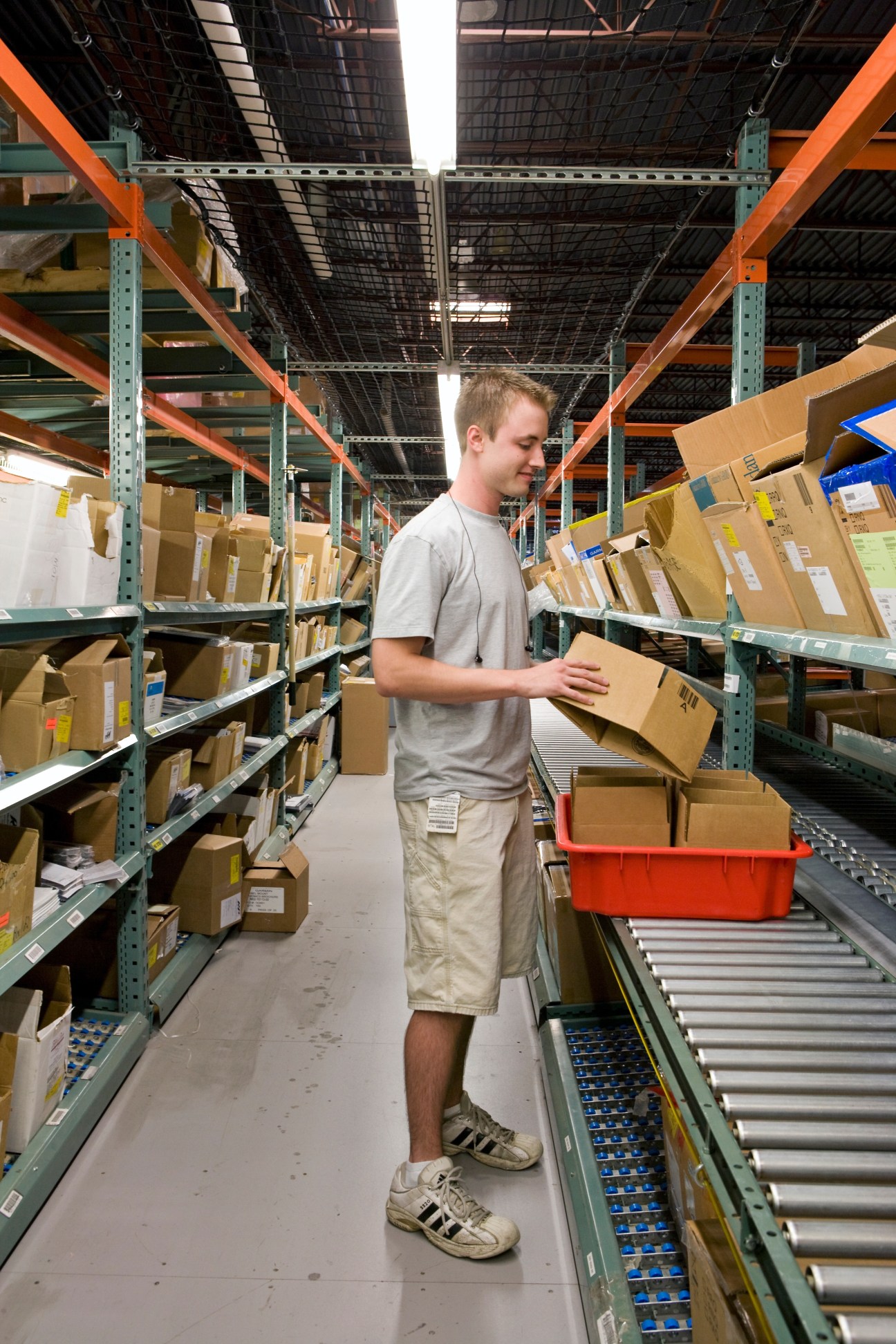 Worker at Garmin International warehouse selecting a cardboard box from shelves.