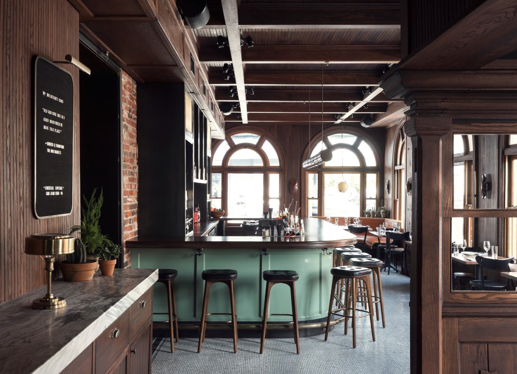 Interior of WM Mulherin's Sons bar with green counter, wooden details, arched windows, and coffered ceiling.