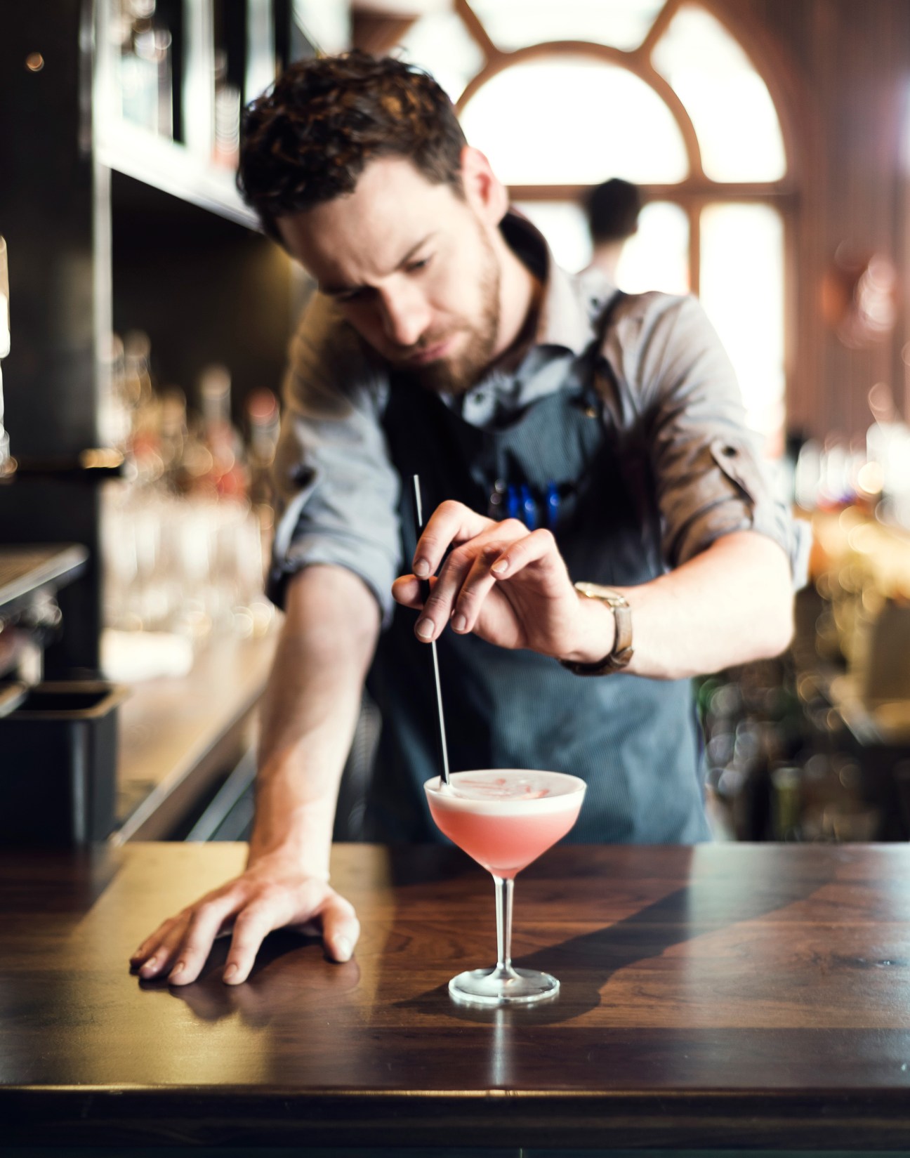 Bartender preparing a pink cocktail at WM Mulherin's Sons bar in Philadelphia.
