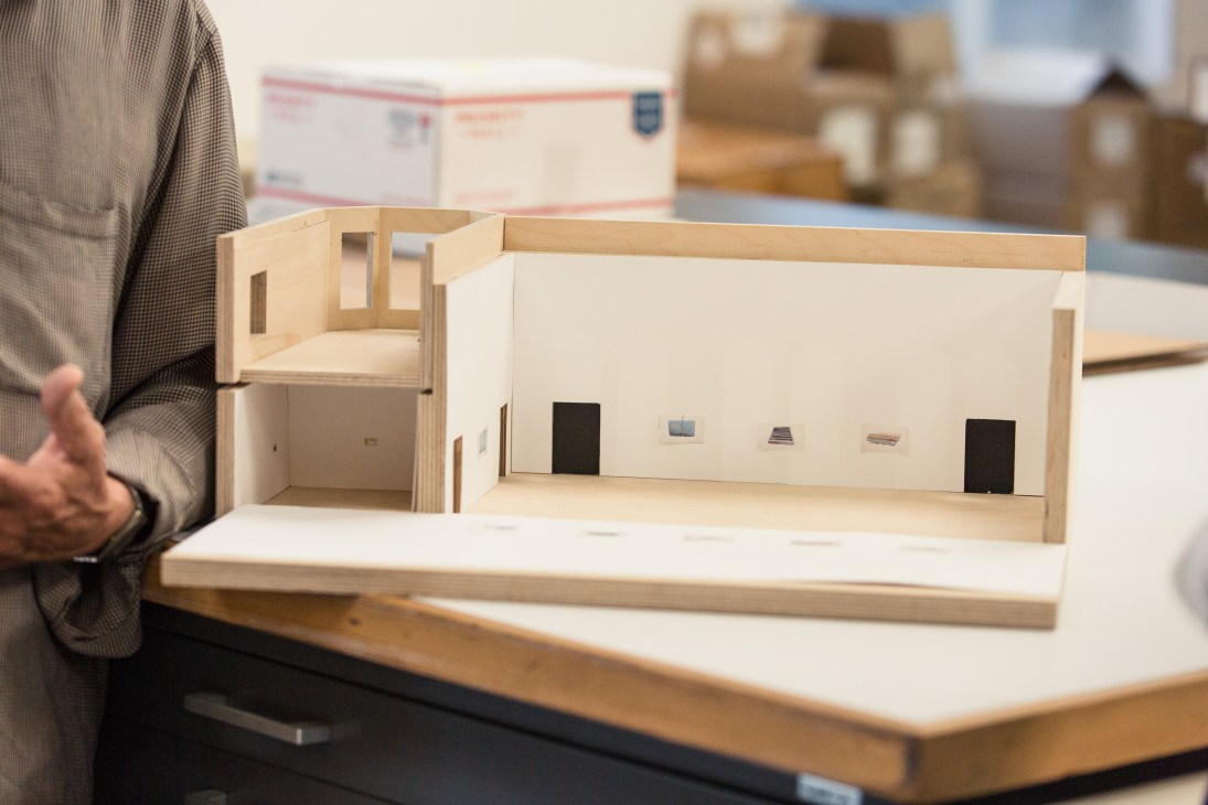 Wooden architectural maquette model for a gallery exhibition displayed on a table in a studio.