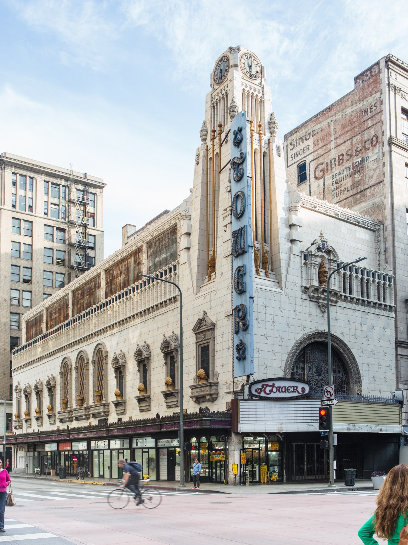 Tower Theater's ornate clock tower and facade with small retail spaces at street level on downtown Los Angeles corner.