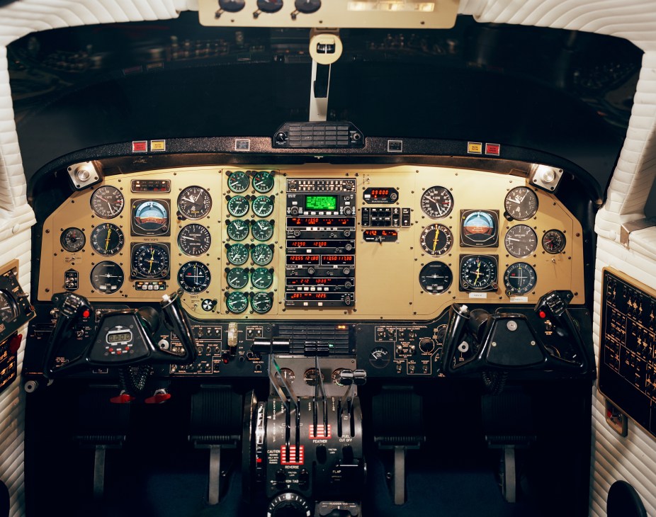 Overhead view of an aircraft flight simulator cockpit with instrument panels, gauges, and controls.