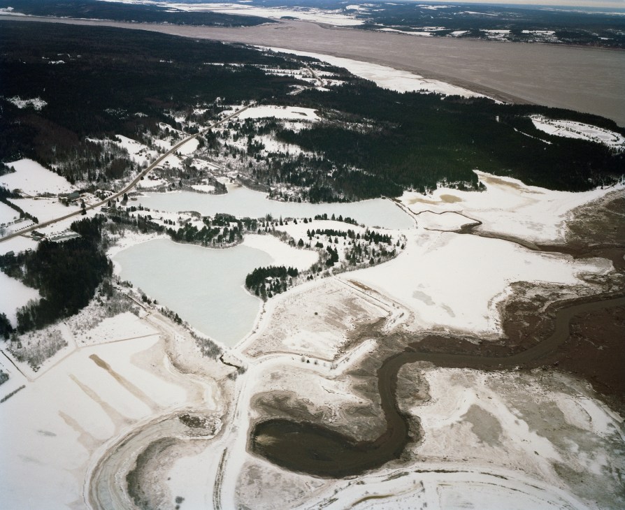 Aerial view of Peticotiac River with snow-covered forests and fields in New Brunswick, Canada.