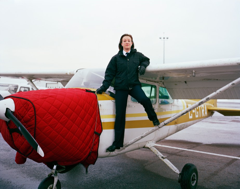 Female pilot student Alexandra Owen stands next to a Cessna aircraft on the runway.