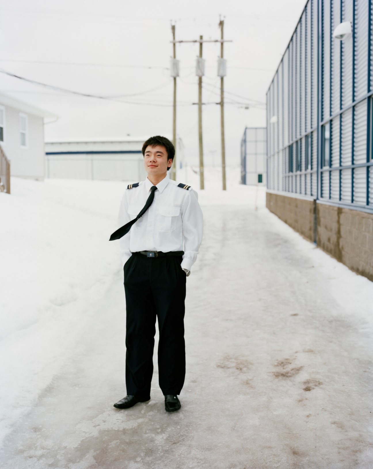 Chinese student Tang Li in pilot uniform standing in snowy courtyard at Moncton Flight College.