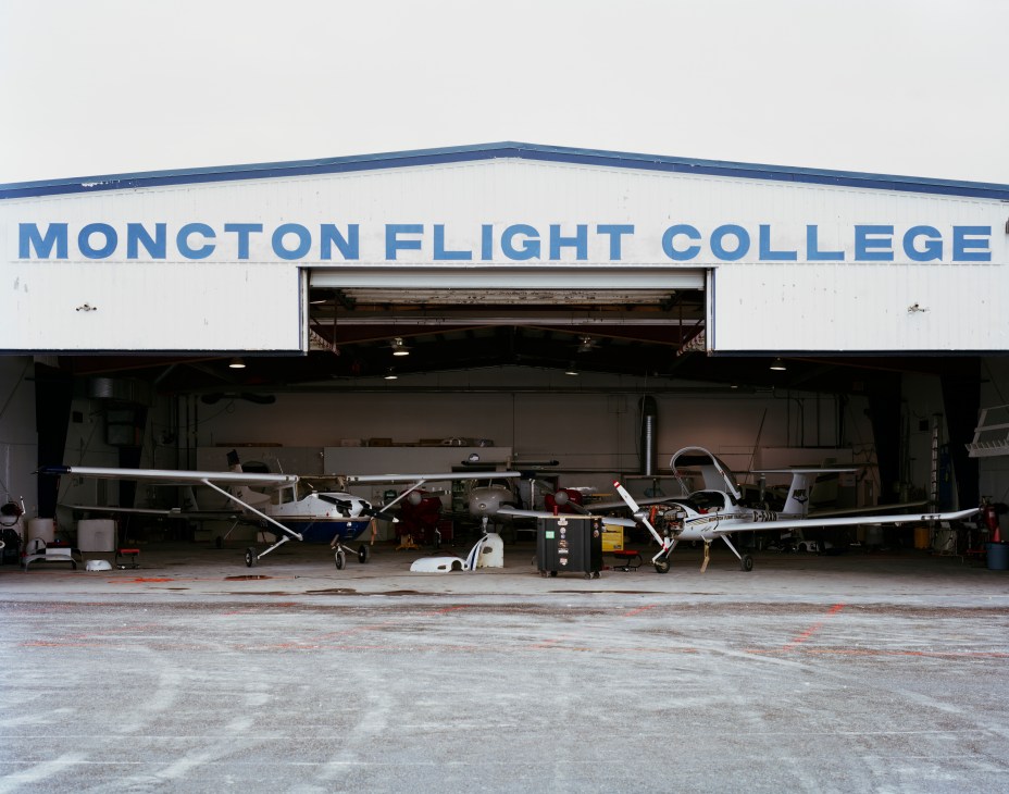 Moncton Flight College hangar with training aircraft parked outside the white building with blue signage.