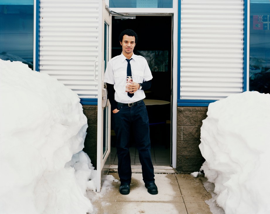 Student Jean Paul Amegashi from Ghana standing in doorway of blue and white building surrounded by snow