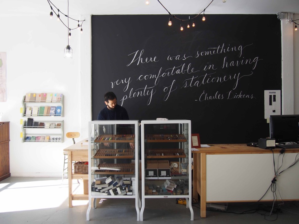 Interior of Wonder Pens stationery store with Charles Dickens quote on black wall and display cases