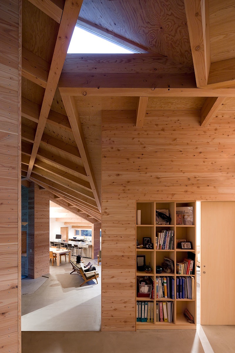 Interior of InBetween House showing wooden beams and bookshelf in Japanese timber construction.