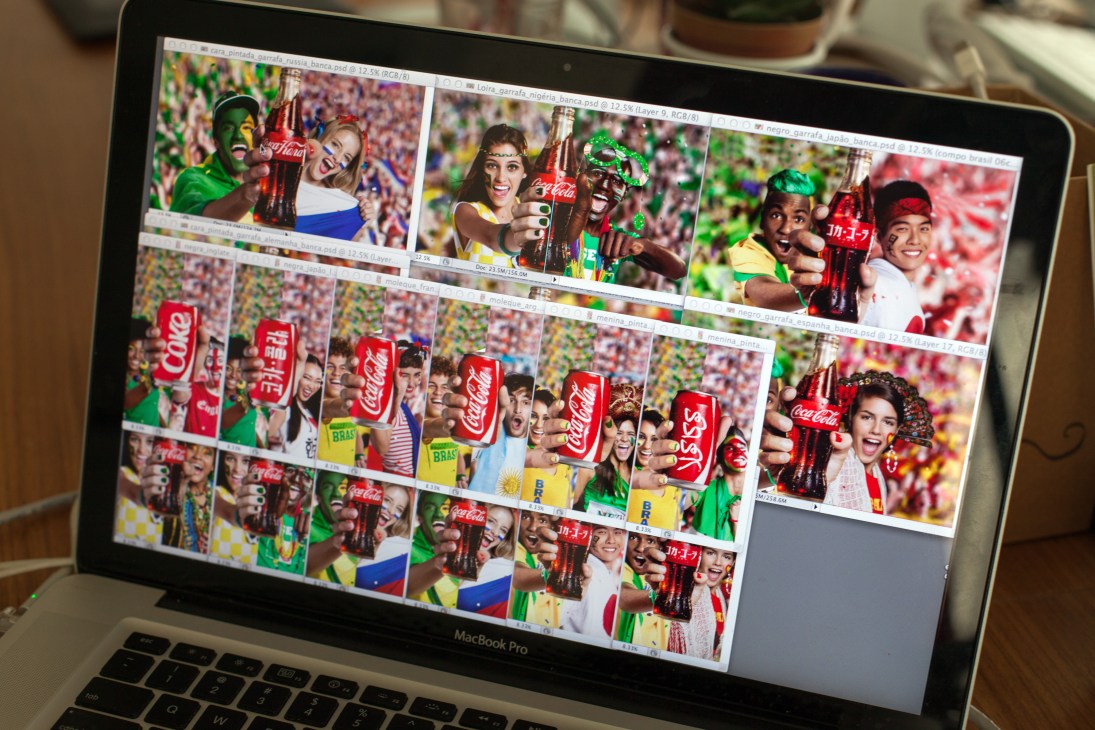 MacBook Pro screen displaying Coca-Cola World Cup campaign images with colored cans and fans in Brazil flag colors.