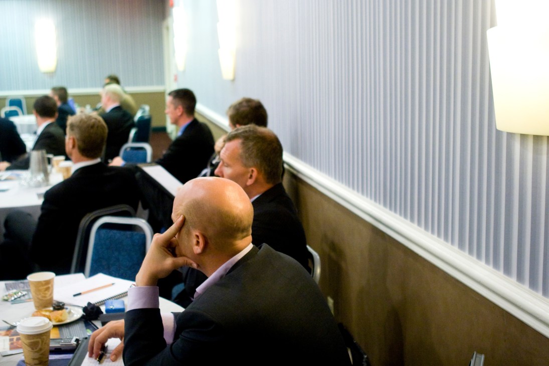 Business professionals in suits seated at a conference table listening to a presentation on African security.