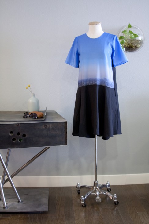 Stahl City dress by wrk-shp displayed on a mannequin, featuring blue top transitioning to black skirt with cityscape print.