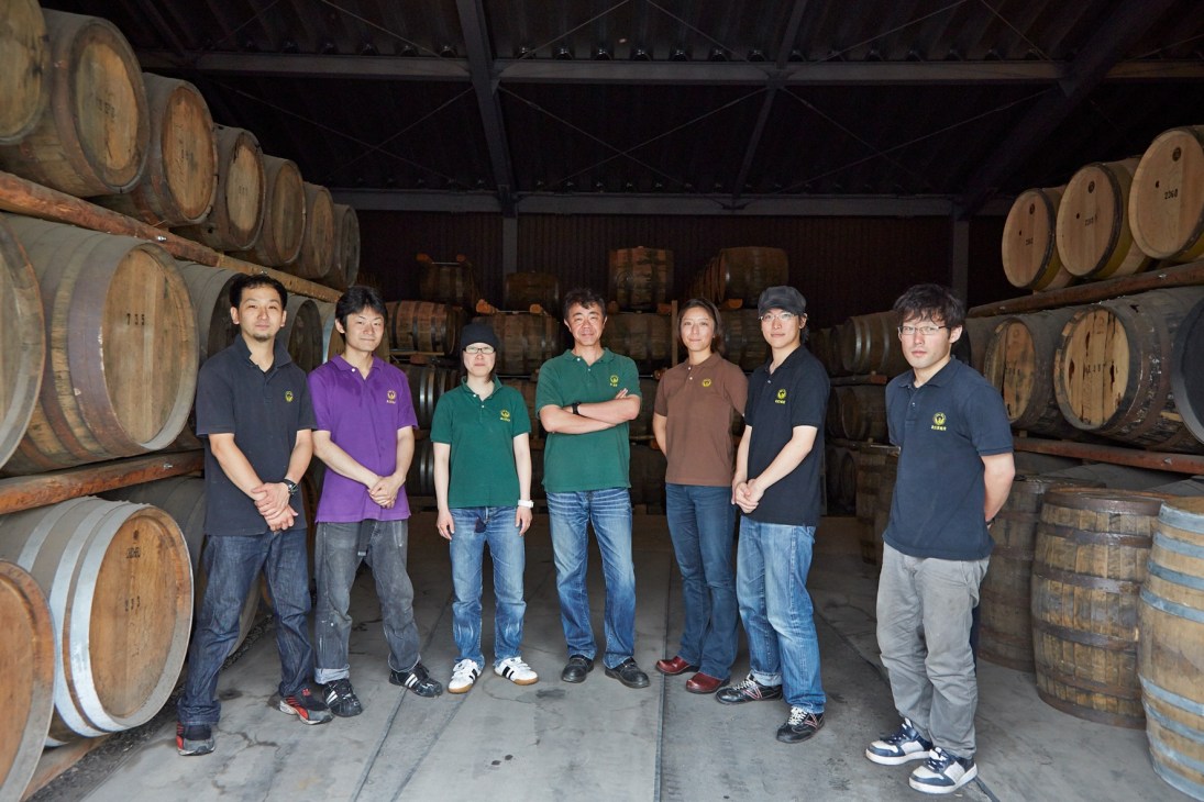 Ichiro Akuto and seven staff members standing in a whisky barrel warehouse at Chichibu Distillery.