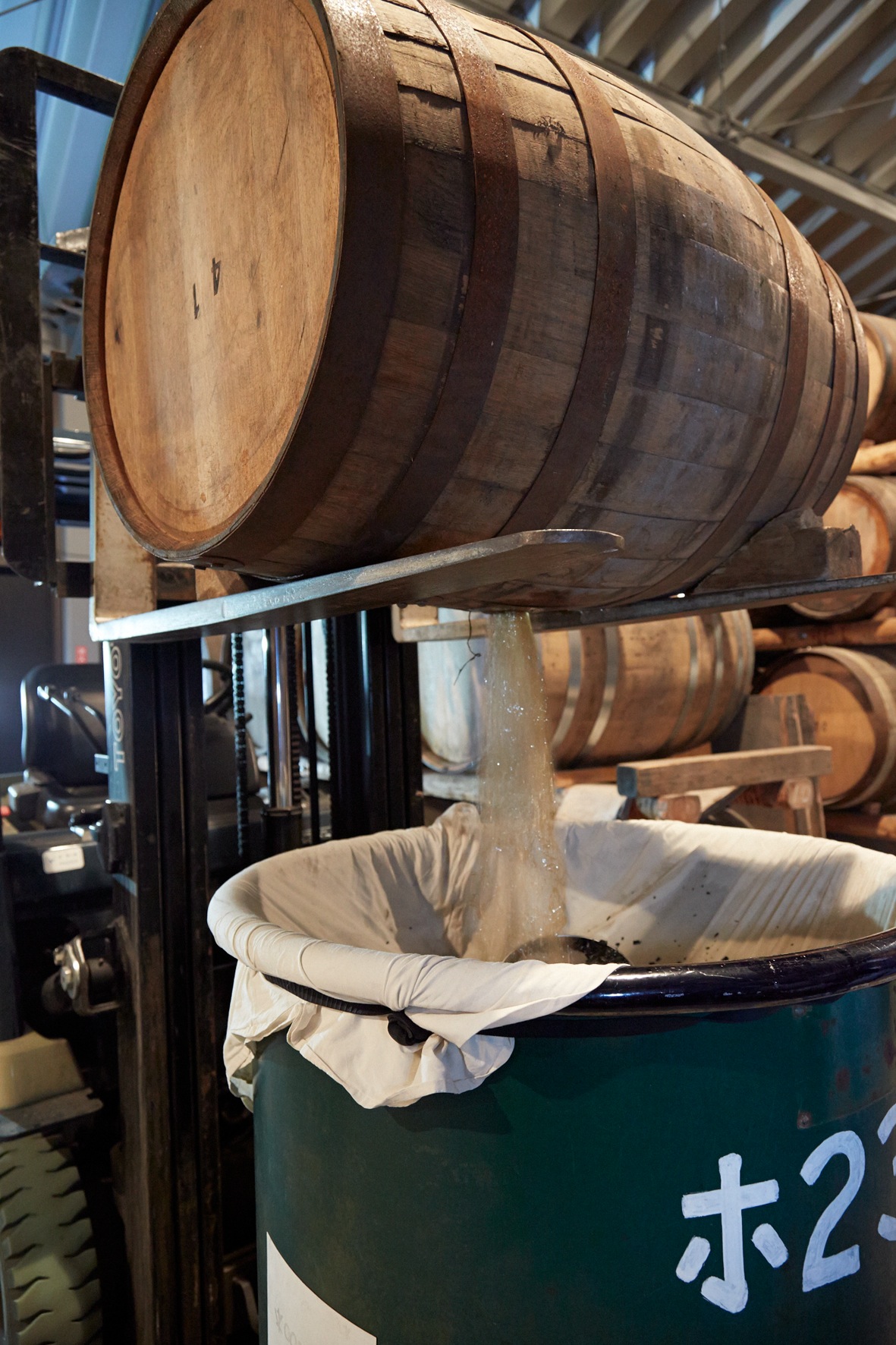 A wooden whisky barrel being drained into a container at Chichibu Distillery.