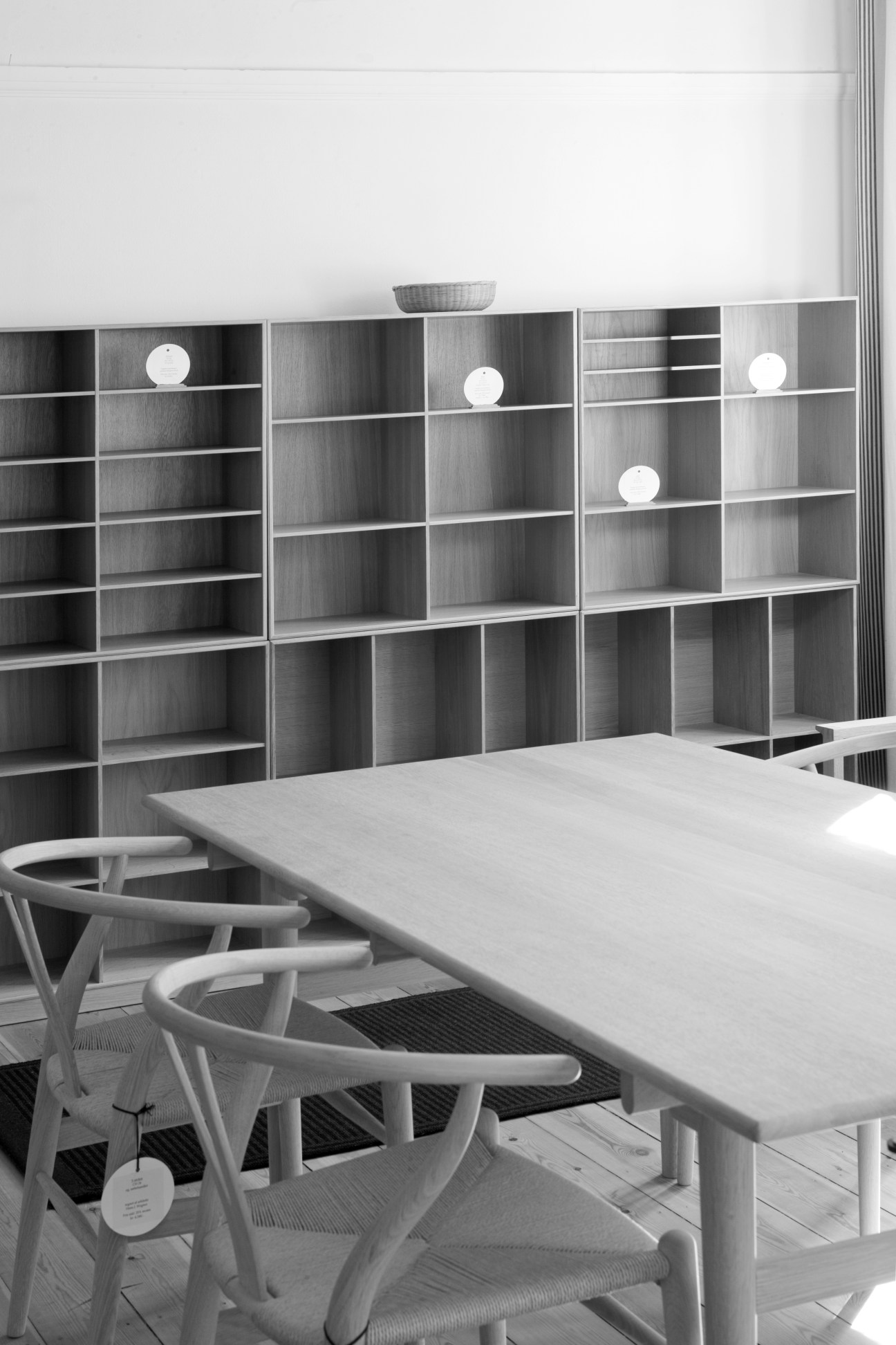 Minimalist workspace with Mogens Koch library shelving system, white desk, and chairs.